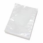 ערימה של שקיות ואקום חלקות למכונות תא ואקום מונחת בצורה מסודרת על משטח לבן, המציגה את איכותם השקופה.