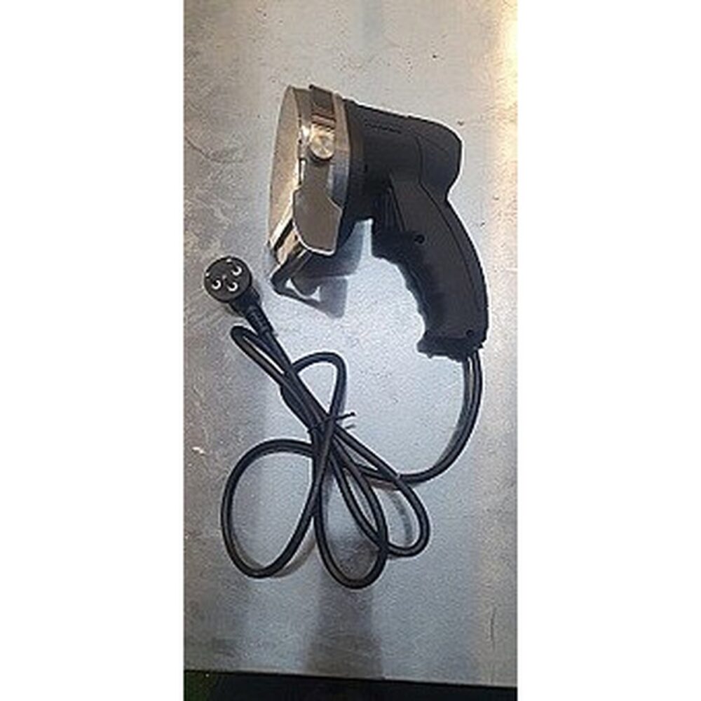 סכין חשמלית ידנית עם להב עגול וידית שחורה, מחוברת לכבל חשמל, מונחת על משטח מתכתי.
