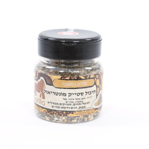 צנצנת פלסטיק שקופה עם מכסה שחור, המכילה תערובת תבלינים עם תווית בעברית, ועליה לוגו של גורילה ותמונה של תבלין לסטייק.